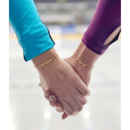 holding hands with gold ice skating bracelets being worn