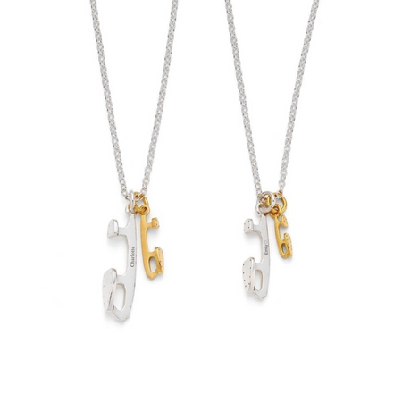 A sterling silver necklace with two ice-skate blades, one in silver and one in gold-plated silver, attached to a chain.