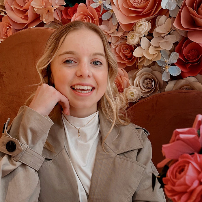 figure skater wearing a mini gold ice skate blade necklace with a flowery background