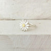 Daisy-shaped ring with a gold center on a wooden surface