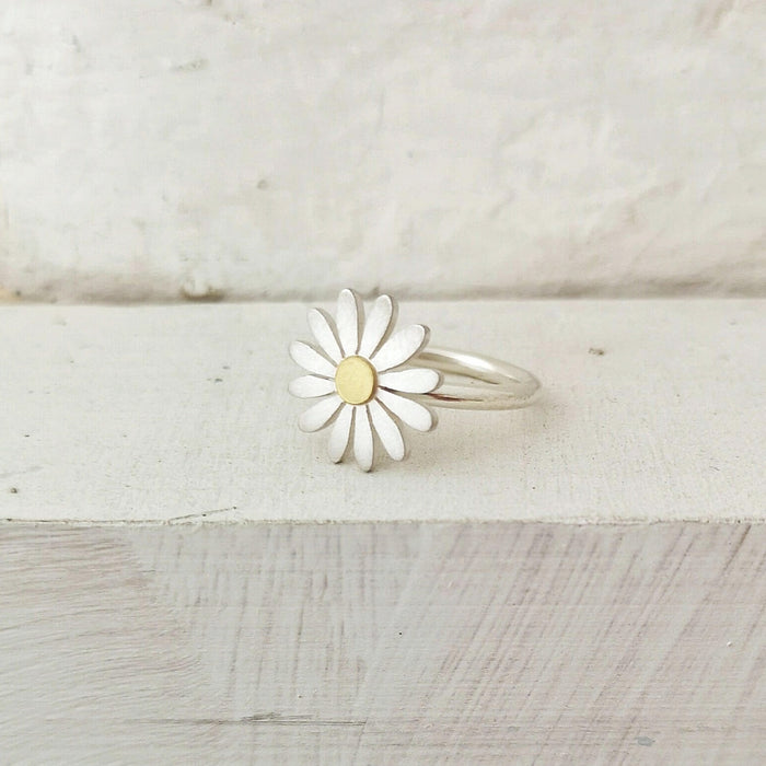 Daisy-shaped ring with a gold center on a wooden surface