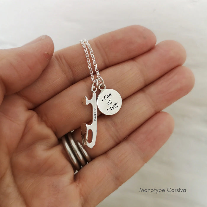 hand holding a silver necklace featuring a personalised ice skate blade and an engraved silver disc charm