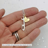 hand holding a personalised silver ice skate blade necklace with a personalised gold plated heart charm