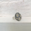 Silver ring with floral design on a textured white surface