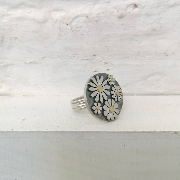 Silver ring with floral design on a textured white surface