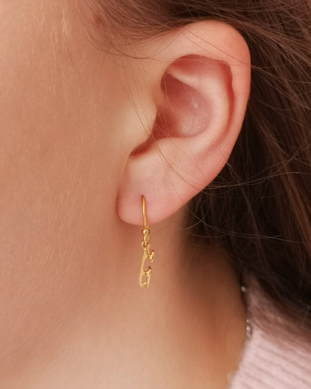 close up of a girl wearing a gold ice skate blade hook earring