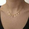 Gold necklace with various charms on a person wearing a black top.