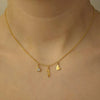 Gold necklace with three charms on a person's neck
