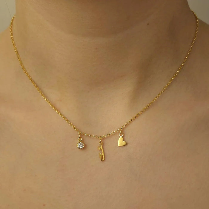 Gold necklace with three charms on a person's neck
