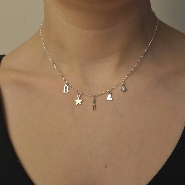 Necklace with various charms including a letter 'B', star, skate blade, and heart on a plain background