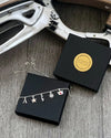 close up of a silver charm necklace on a presentation box with ice skates in the background