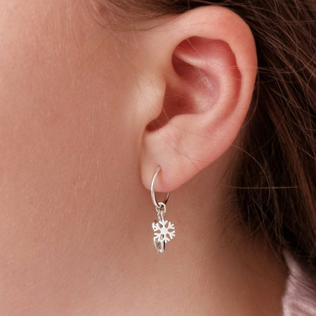 close up of a girl wearing a silver ice skate blade and snowflake hoop earring